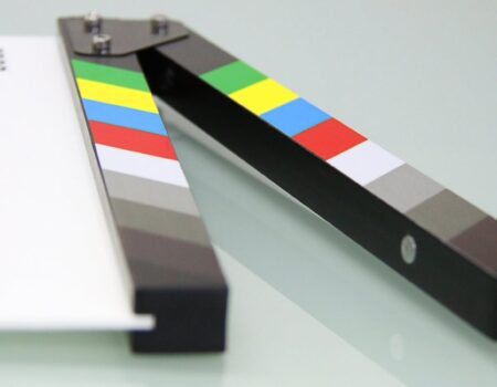 Colorful clapper board on a white surface, used in filmmaking. Ideal for entertainment and movie themes.