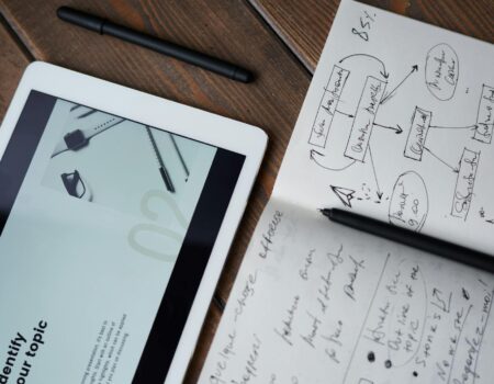Digital and handwritten brainstorming tools on a wooden desk, ideal for business and study contexts.